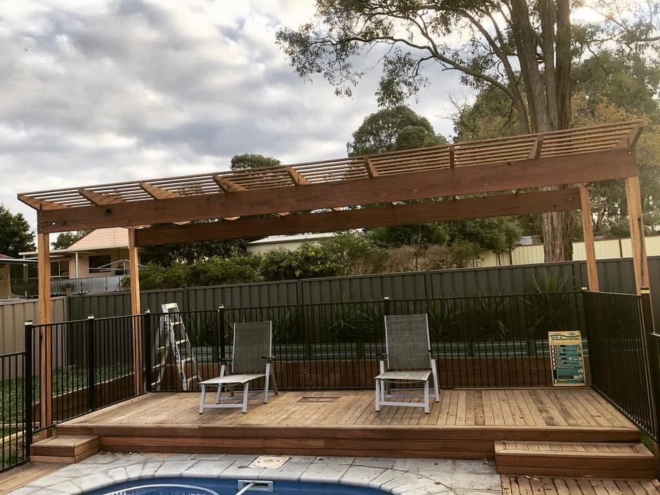 Hardwood timber pergola with slatted roof over a poolside deck in Charlestown