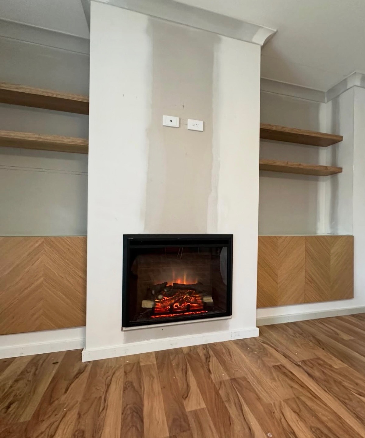 Custom fireplace surround with floating timber shelves and herringbone panelling
